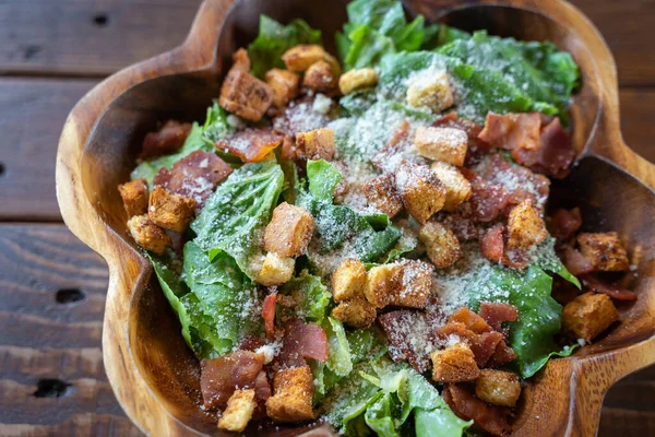 Salamlı Sezar salatası ahşap bir kasede, zeytinyağı, limon suyu, çiğ yumurta, parmesan peyniri ve Sezar soslu baharatlarla servis edilir. Uluslararası lezzetli yiyecekler.