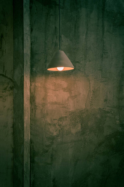 Beautiful modern ceiling lamp lights bulbs triangular shape decoration on cement wall loft-style with space for text by vintage mood toning color. Contemporary interior for office building concept.