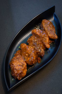 Siyah arka planda servis edilen siyah bir tabakta soslu tavuk dolması..