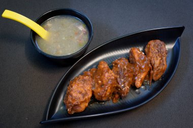 Tavada kızarmış tavuk ve siyah bir tabakta servis edilen siyah arka plandaki tavuk çorbası..