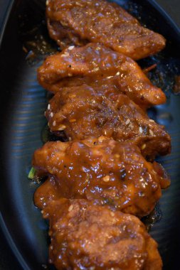 Siyah arka planda servis edilen siyah bir tabakta soslu tavuk dolması..