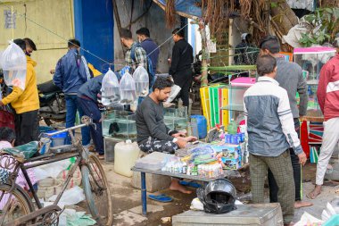 Kimliği belirsiz bir Hintli satıcı, Aralık 2021 'de Hindistan' ın Kolkata kentindeki Galiff Caddesi evcil hayvan pazarında dekoratif balık akvaryumu için aksesuar satıyordu.