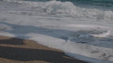 Genç bir çift deniz kenarında koşuyor ve eğleniyor. Denizde ve kumda çıplak ayakla koşarlar. Yaz, tatil ve sahil konsepti. Yavaş çekim, 4K