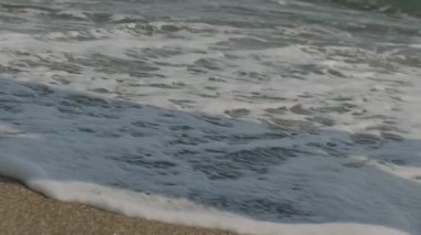 Genç bir çift deniz kenarında koşuyor ve eğleniyor. Denizde ve kumda çıplak ayakla koşarlar. Yaz, tatil ve sahil konsepti. Yavaş çekim, 4K