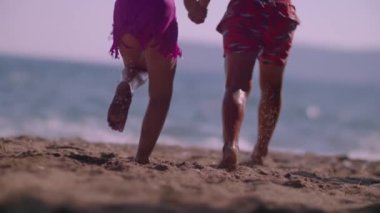 Deniz kenarında koşan çocuklar. Çocuklar denizde koşuyor, kıyılarında ve sahillerinde. Sahilden denize koşuyorlar. Yavaş çekim ve yüksek kalite