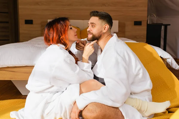 Genç ve sevgi dolu bir çift otelin yatağının yanında yüz yüze oturuyorlar..