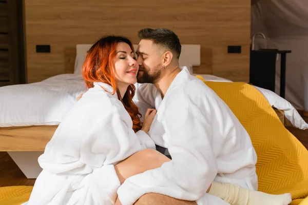 Joven Pareja Cariñosa Abrazándose Sentado Cara Cara Suelo Cerca Cama — Foto de Stock