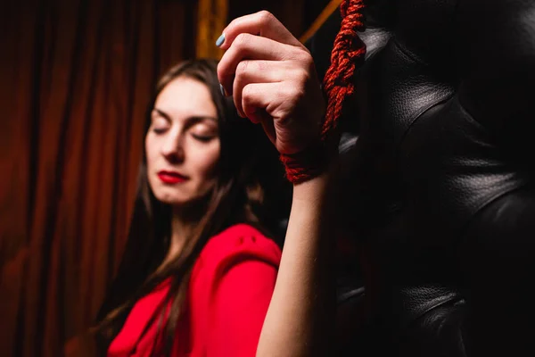 Bondage woman tied to bed with red ropes. Close-up of a woman\'s hand tied to the bed.