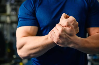 Spor salonundaki adamın kaslı elleri ve yumrukları, dar tişörtler giyen güçlü güçlü erkek antrenör iç mekanda antrenör.