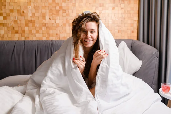 Atractiva Mujer Joven Positiva Sonriendo Mientras Está Sentada Cama Cubriéndose — Foto de Stock