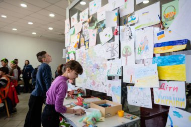 Dnipro, Ukrayna - Nisan 04, 2022: Çocuklar Dnipro 'daki bir Mülteci Yardım Merkezi' nde resimler çiziyor. Ukrayna 'daki savaşa karşı çocuk çizimleri olan duvar..