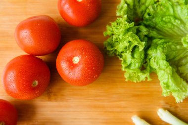 Salata için taze sebzeler kesim tahtasıyla birlikte ahşap bir masada yatıyor. Üst Manzara. Yakın plan..