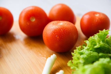 Salata için taze sebzeler kesim tahtasıyla birlikte ahşap bir masada yatıyor. Yakın plan..