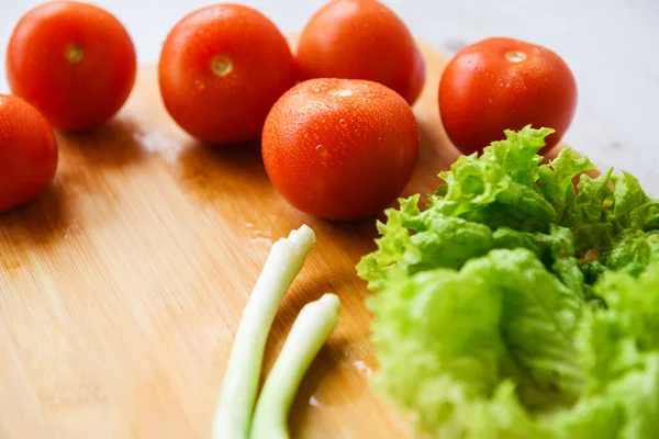 Salata için taze sebzeler kesim tahtasıyla birlikte ahşap bir masada yatıyor. Yakın plan..