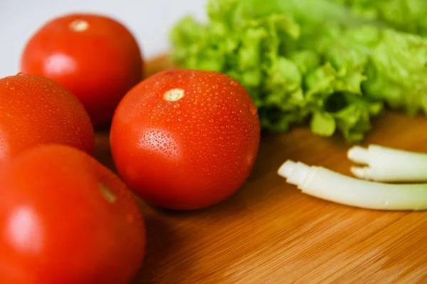 Salata için taze sebzeler kesim tahtasıyla birlikte ahşap bir masada yatıyor. Yakın plan..