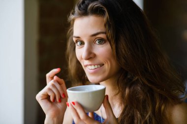 Güzel bir kız çay içer, tadını ve kokusunu alır. Kız bir kahve dükkanında kahvaltı yapıyor..