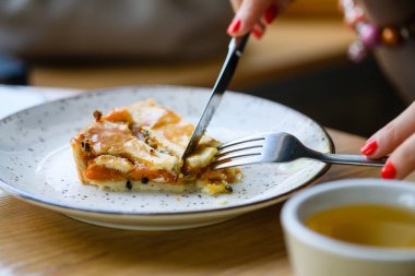 Kahve dükkanlarında kahvaltı. Çatal ve bıçakla kadın eli. Kız kahvaltını bir kafede yapar, turta yer ve çay içer..