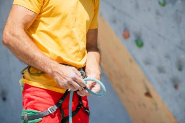 Bir adam tırmanma rotasına tırmanmaya hazırlanıyor. Kaya tırmanışında sigorta ve güvenlik. Güvenlik halatı. Düğüm sekiz.