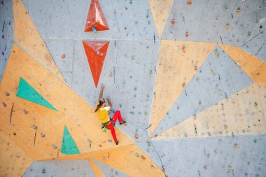 Genç ve formda bir adam dışarıda dağ tırmanışı yapıyor. Duvara tırmanan adam.