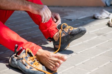 Kaya tırmanıcısı tırmanma ayakkabıları ve kravat bağcıkları giyer. Tırmanmaya hazırlanıyorum. Erkek elleri yakın plan.