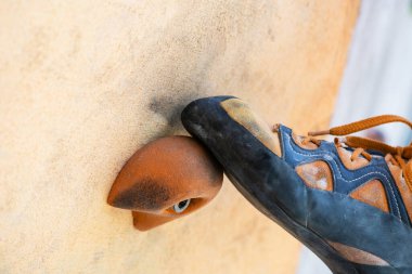 Close-up of climbing shoes training in artificial climbing wall outdoors. Climber detail.