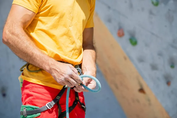 Bir adam tırmanma rotasına tırmanmaya hazırlanıyor. Kaya tırmanışında sigorta ve güvenlik. Güvenlik halatı. Düğüm sekiz.