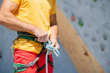 Bir dağcı düğüm atar. Bir adam tırmanma rotasına tırmanmaya hazırlanıyor. Kaya tırmanışında sigorta ve güvenlik. Güvenlik halatı. Düğüm sekiz.