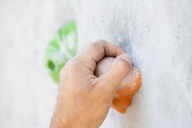 Magnezyum tozu bulaşmış bir erkek eli, tırmanma duvarını tutuyor..