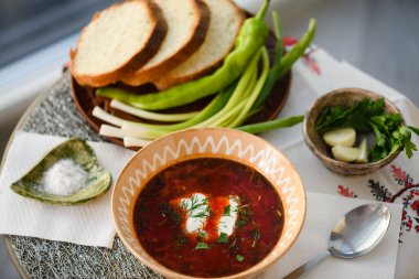 Traditional Ukrainian borscht. Clay Bowl of red beet root soup borsch with white cream.