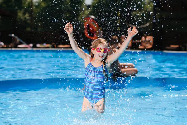 小さな女の子の子供で水着やゴーグルで遊ぶで水でプール スプラッシュや笑いを作る 幸せな夏休み — ストック写真