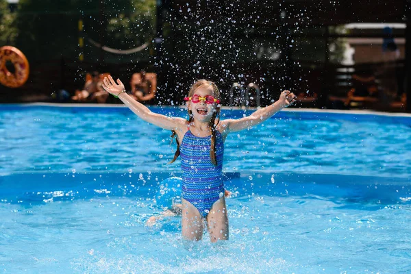 小さな女の子の子供で水着やゴーグルで遊ぶで水でプール スプラッシュや笑いを作る 幸せな夏休み — ストック写真