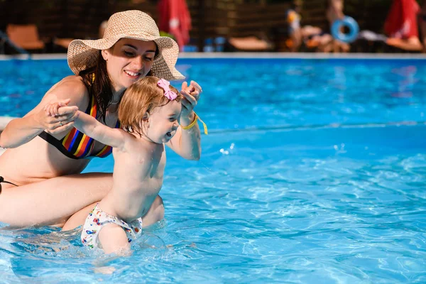 若いですお母さんはプールで幼児の女の子の子供と遊ぶ 夏の家族の活動と幸せな子供時代 — ストック写真