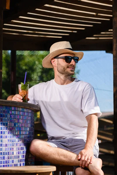 Νεαρός Χαμογελαστός Άνδρας Γυαλιά Ηλίου Και Ψάθινο Καπέλο Πίνοντας Κοκτέιλ — Φωτογραφία Αρχείου