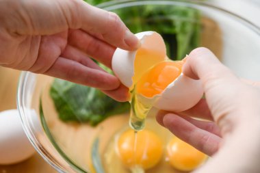 Cam bir kasede yumurta kıran bir çift kadının yakın çekimi..