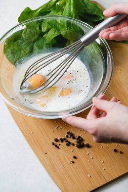 Genç bir kadın cam kasede çırpıcıyla yumurta çırpıyor. Omlet pişiriyorum. Yukarıdan görüntüle.