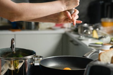 Kadın evde kahvaltı yaparken tavaya tuz atıyor..