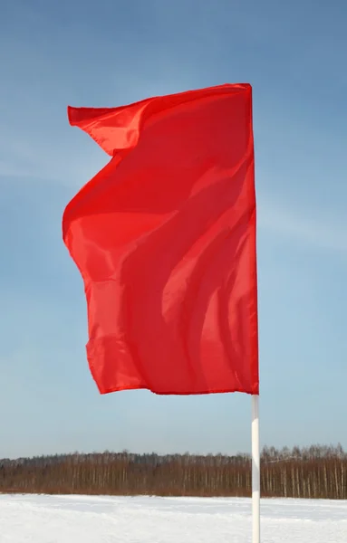 One red flag flutters in wind at background of blue pure sky, sn — Stock Photo, Image