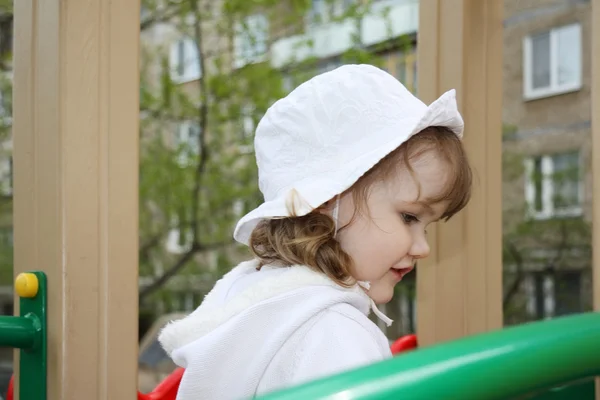 Beautiful little girl wearing white blouse plays at playground — Stock Photo, Image