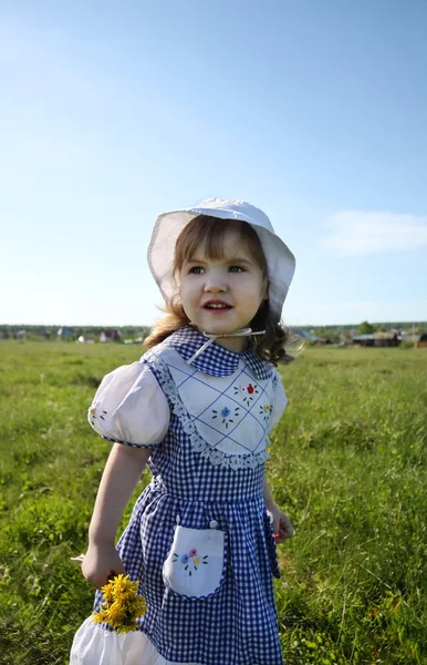 Happy little girl wearing dress looks into distance on green fie — Stock Photo, Image