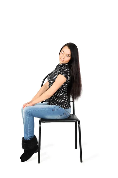 Piękna dziewczyna dzinsach siedzi na krześle na białym tle na biały bac — Zdjęcie stockowe