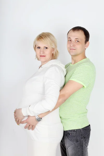 Happy pregnant wife in white and husband hold belly on white bac — Stock Photo, Image