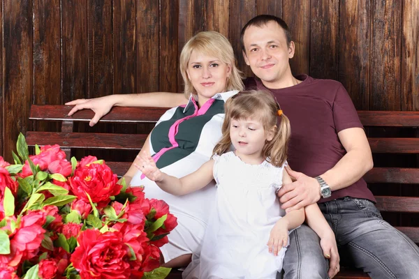 Father, pregnant mother and little daughter sit on bench next to — Stock Photo, Image