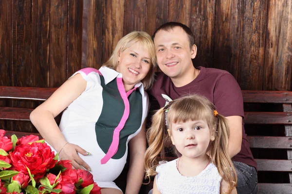 Happy father, pregnant mother and surprised daughter sit on benc — Stock Photo, Image