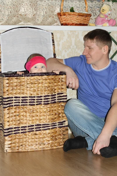 Kleines Baby sitzt in großem Weidenkorb und ihr glücklicher Vater schaut sie an — Stockfoto