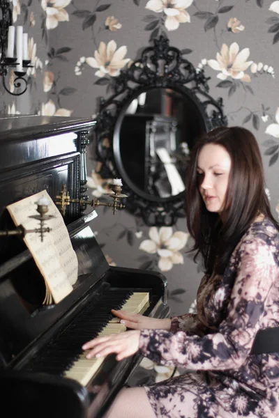 Hermosa joven morena en vestido toca el piano y canta. F — Foto de Stock