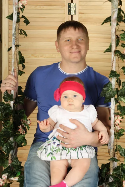 Happy father with cute baby sits on swing overgrown with green i — Stock Photo, Image