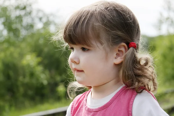 Little cute girl in pink dress thinks and looks away at summer d — Stock Photo, Image