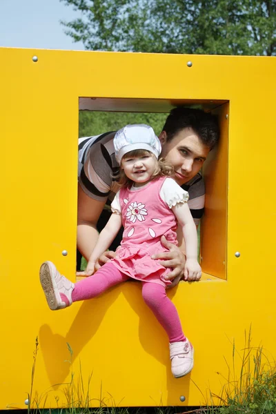 Happy little girl with father sits in window of yellow box at pl — Stock Photo, Image