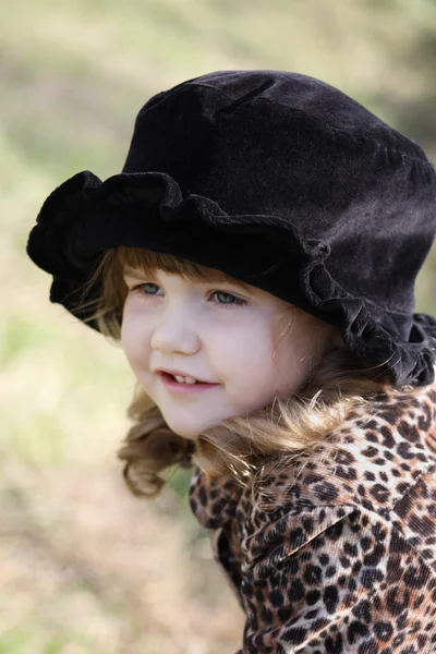 Beautiful little girl in black hat looks away outdoor at autumn — Stock Photo, Image