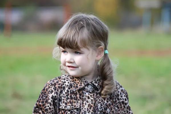 Pequena menina bonito em overcoat olha para a distância no dia de outono . — Fotografia de Stock